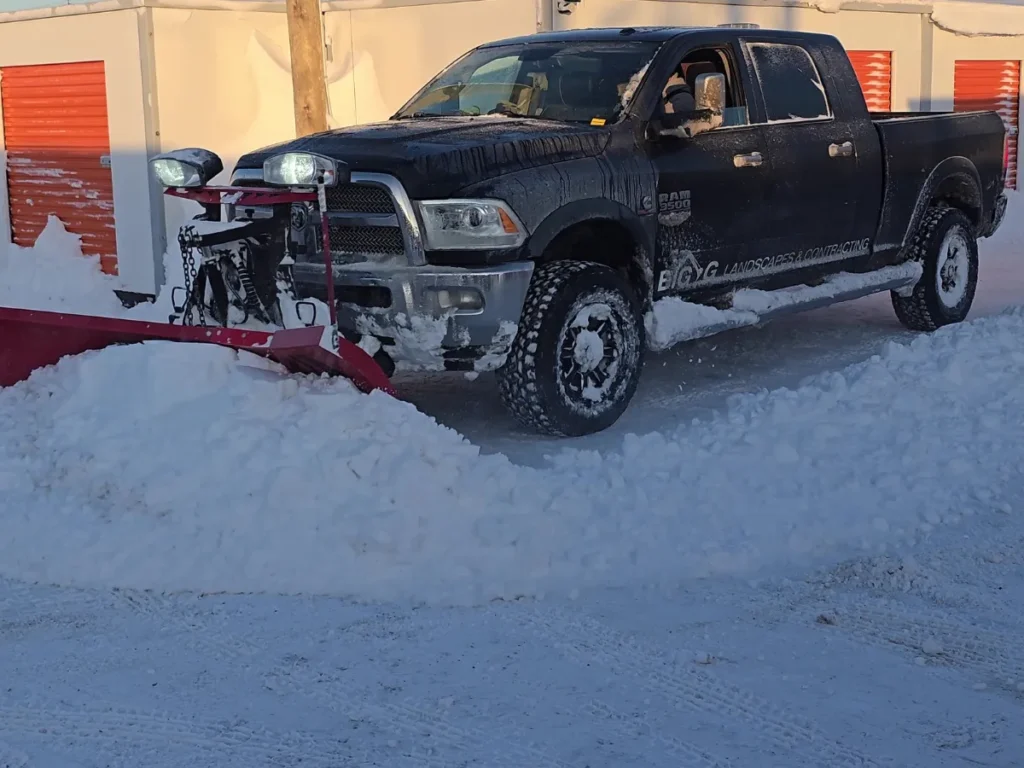 Black Dodge Ram plowing snow in front of storage units.