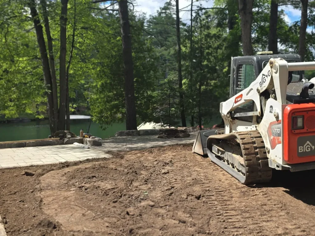 Big G Landscapes skid steer working on a lakeside hardscape and grading project.