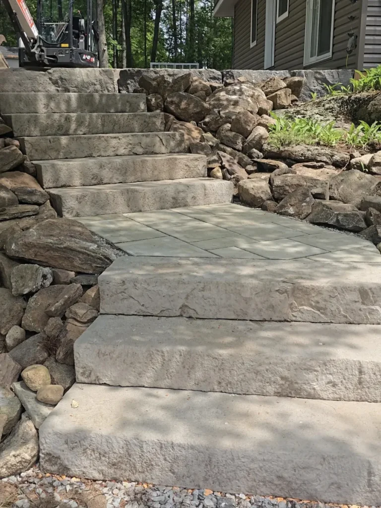 Stone staircase with retaining rockwork beside a house.